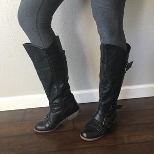 Knee high modest black boots with buckles.